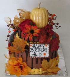 a birthday cake decorated with fall leaves, flowers and a sign that says happy birthday hedi