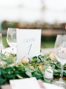 the table is set with wine glasses and greenery for an elegant touch to the place setting