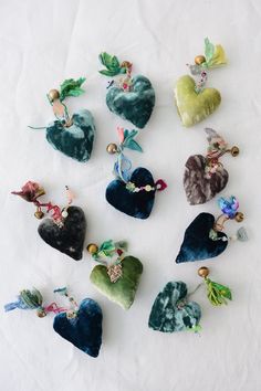 nine heart shaped brooches are arranged on a white surface with beads and leaves