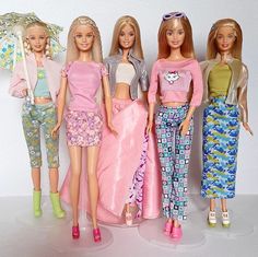 four barbie dolls standing next to each other