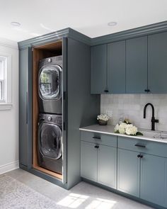 a washer and dryer are in the middle of a kitchen with blue cabinets