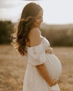 a pregnant woman is standing in a field