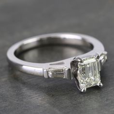 an engagement ring with three baguets on the side and one stone in the middle