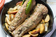 two steaks and potatoes in a skillet on a stove top with tongs