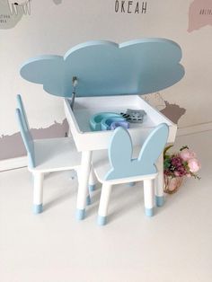 a blue and white toy table with two chairs next to it in front of a cloud shaped wall