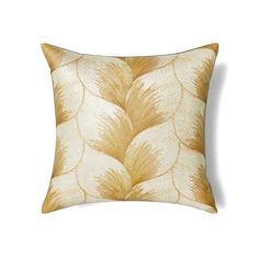 a gold and white pillow with large leaves on it