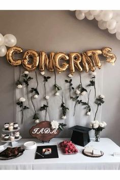 a table topped with balloons and flowers next to a sign that says congrats