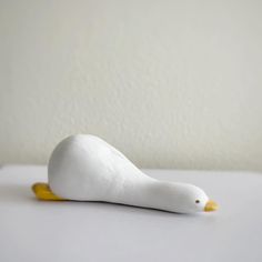 a white bird sitting on top of a table next to a yellow object in the shape of a duck