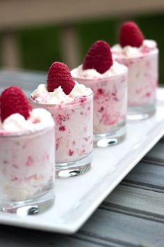 small desserts with raspberries and whipped cream in them on a white tray