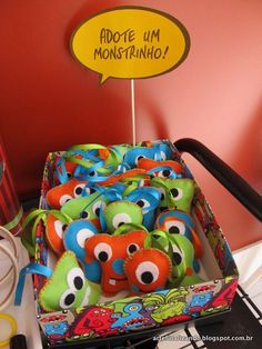 there is a box full of stuffed animals on the table with a sign above it that says adopte um monstrino