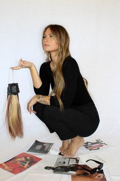 a woman sitting on the floor with her hair in one hand