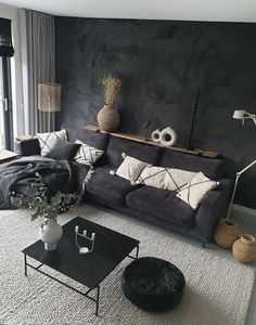 a living room with black walls and white rugs on the floor, two vases sitting on top of a coffee table