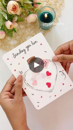 two hands holding up a card with an image of a bird and hearts on it