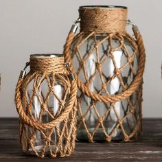 three glass vases with rope wrapped around them on a wooden table next to each other