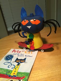 a toy cat sitting on top of a wooden table next to a book