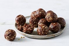 a plate filled with chocolate covered balls on top of a white table next to some nuts