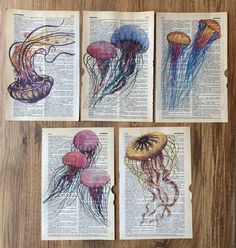 four jellyfishs on an open book with watercolor pencils in them, sitting on a wooden table