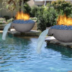 two fire bowls sitting on top of a swimming pool