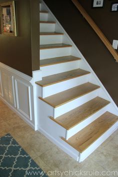 the stairs in this house are painted white and have wood treading on them, along with carpeted flooring