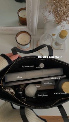 the contents of a black purse sitting on top of a table next to a mirror