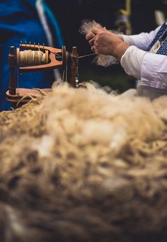 a man is spinning wool on a spinning wheel with a needle in his right hand