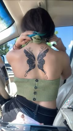 a woman sitting in the back seat of a car talking on her cell phone while wearing a green crop top