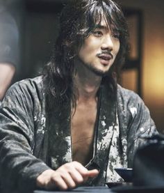 a man with long hair sitting at a table