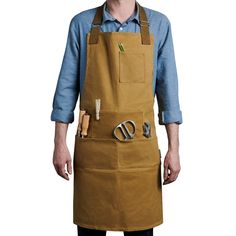 a man wearing an apron with scissors in his pocket and one hand on his hip