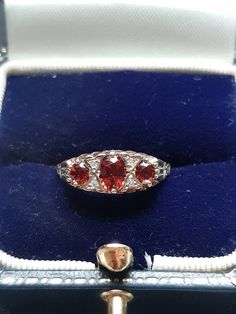 A vintage 9ct gold garnet and diamond ring. The ring is Hallmarked 9ct gold. The largest oval cut garnet is claw set at the centre and measures 5 x 4mms. The outside garnets each measure 4 x 3mm's. Flanking the central garnet on both sides are two round brilliant cut diamonds. These four diamonds have an estimated combined weight of 0.08ct's. Finger size N, but we can make the ring bigger, or smaller. Victorian Oval Red Diamond Ring, Victorian Style Red Oval Diamond Ring, Vintage Oval Garnet Birthstone Ring, Vintage Oval Three-stone Ruby Ring, Antique Red Oval Diamond Ring, Antique Oval Red Diamond Ring, Hallmarked Red Oval Sapphire Ring, Hallmarked Oval Red Sapphire Ring, Vintage Oval Birthstone Diamond Ring