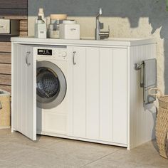 a washer sitting inside of a white cabinet next to a laundry basket and towel dispenser