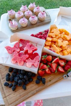 a variety of fruits are displayed on a table with cupcakes and muffins