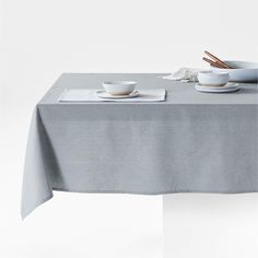 the table is set with two cups and saucers on it, along with napkins