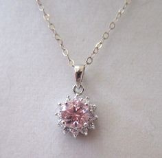 "Don't take your good jewelry with you on vacation when you can still look elegant in CZs! This necklace features a pink Cubic Zirconia solitaire stone surrounded by clear CZ stones. All are set into an 18K setting and hang from a sterling silver chain. The back of the pendant is marked 18K and the chain sterling silver. The length of the pendant is 18\" when worn and the pendant drop itself measures 1/2\" in diameter. Well-made and in excellent condition." Pink And Silver Necklace, Silver And Pink Jewelry, Dazzling Pink Gemstone Jewelry, Pink Diamond Jewelry With Prong Setting, Sterling Silver Necklace With Center Stone For Weddings, Pink Diamond Dainty Necklace, Dainty Pink Diamond Necklace, Pink Cubic Zirconia Formal Jewelry, Pink Cubic Zirconia Jewelry For Formal Occasions