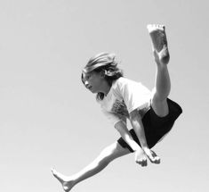 a woman is jumping in the air with her legs spread out and one leg up