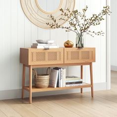 a wooden table topped with a vase filled with flowers next to a wall mounted mirror