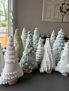 small white christmas trees are lined up on a table in front of a window,