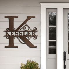 the letter k is mounted to the side of a house with two potted plants