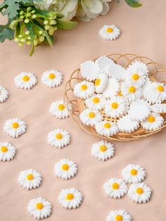 small white and yellow flowers sitting on top of a table next to a basket filled with petals