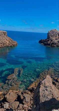 the water is crystal blue and clear with rocks on both sides, as well as an island in the distance