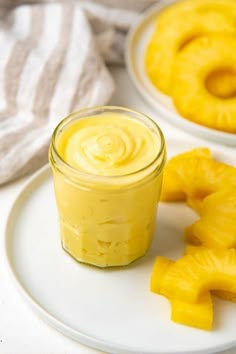 a jar of pineapple butter on a plate next to two slices of pineapple