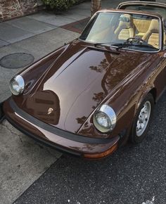 a brown sports car is parked on the street