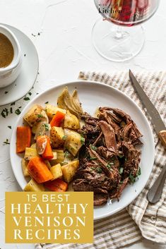 a white plate topped with roast, potatoes and carrots next to a glass of wine