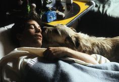 a man laying in bed with his dog