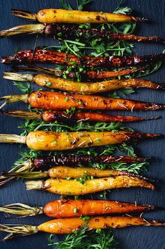 carrots are lined up on a blue surface with herbs and seasonings in them