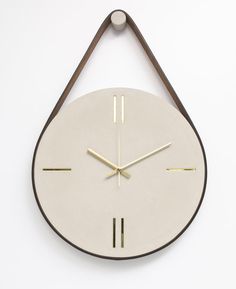 a white clock hanging on the wall with gold hands and two bars at the bottom