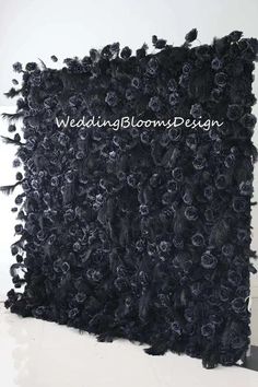 a black backdrop with flowers and feathers on the wall for a wedding or special event