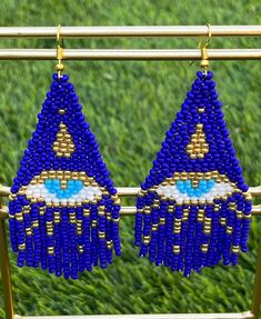 two pairs of blue beaded earrings hanging from a metal rack on grass covered ground