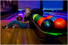 a woman sitting on the ground next to bowling balls