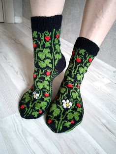 a person wearing green socks with red flowers on them