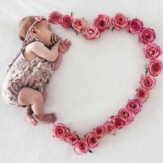 a baby is laying in the shape of a heart with roses on it's side